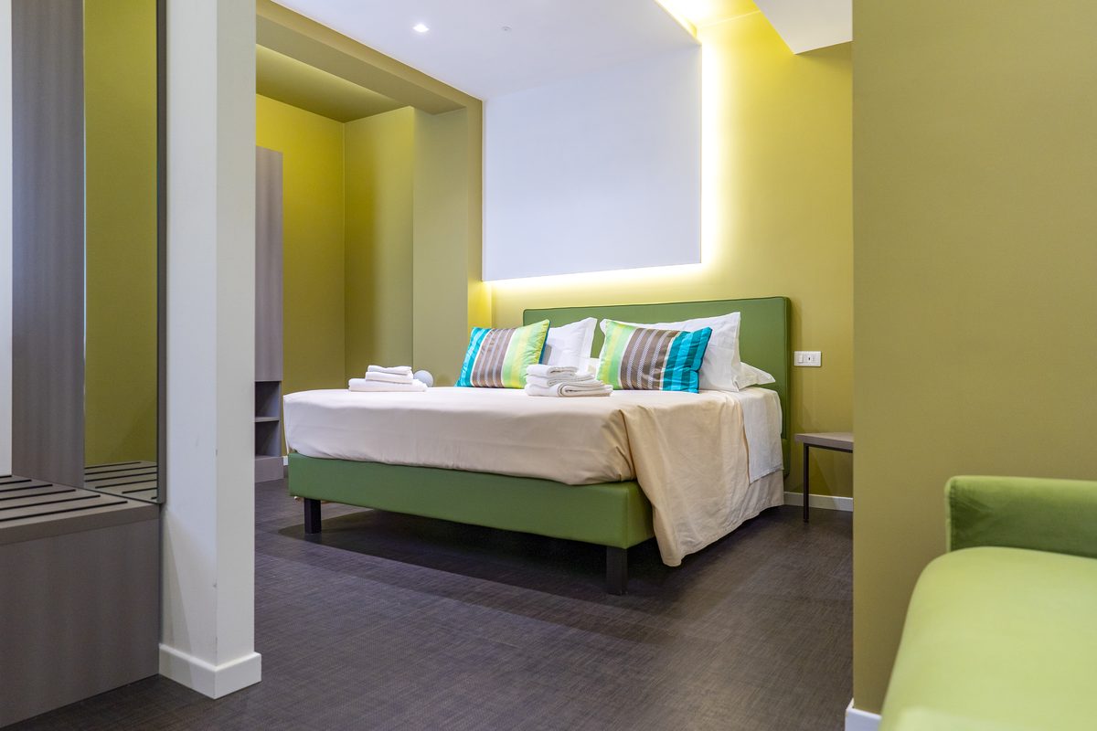 Camera dell'hotel con parete verde e letto matrimoniale